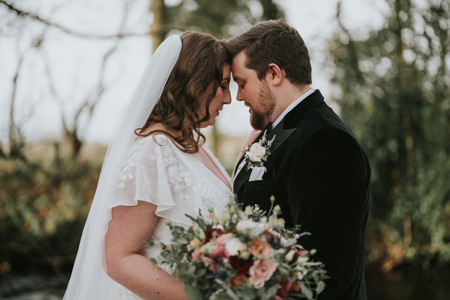 Bride and groom touching foreheads beside the river at The Wool Tower in winter