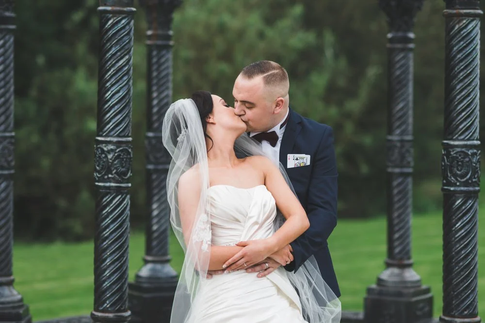 Bride and groom kissing between black wrought iron pillars at their Dunsilly Hotel wedding near Antrim