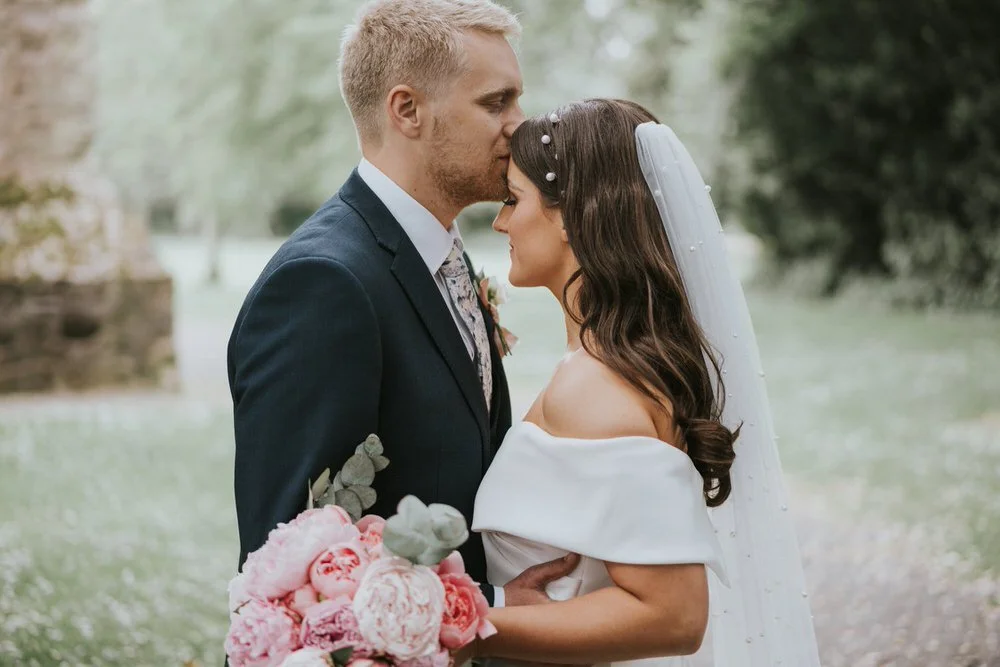 Rachel and David close together, David kissing her forehead, Rachel wearing a veil with pearl details