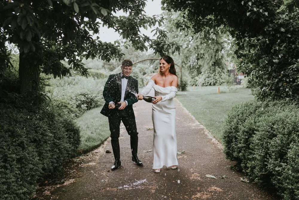 Bride and groom walking hand in hand along a leafy garden path on their Belfast City Hall wedding day