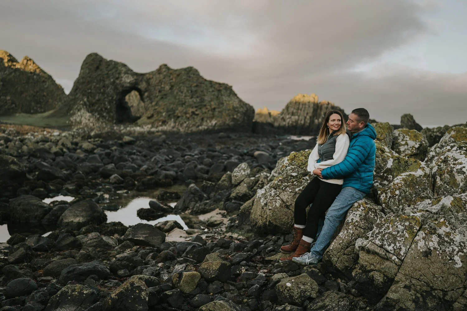 Couple walking together beside Ballintoy Harbour on the Northern Ireland coast