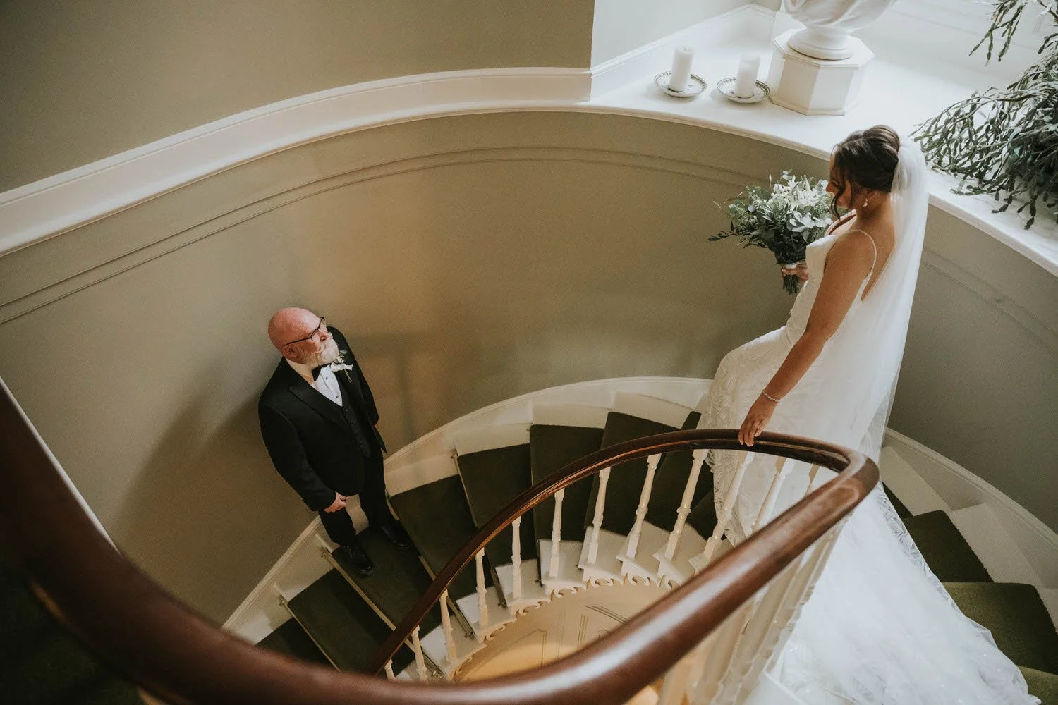 Bride on the curved staircase at Tullyveery House with the groom waiting below