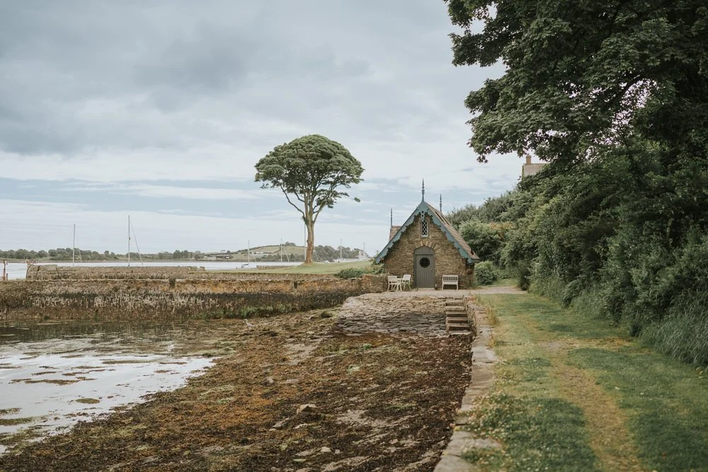 Stone boathouse beside the harbour and a lone tree on the shore of Strangford Lough at Old Court