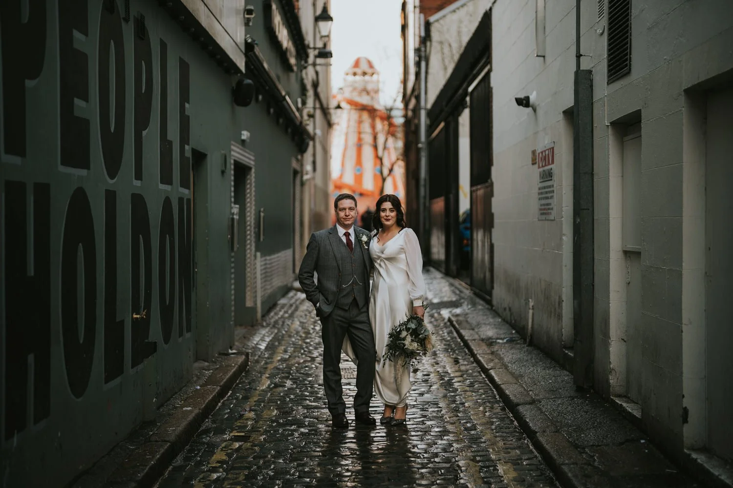 Newlyweds walking down a narrow cobbled lane in Belfast city centre