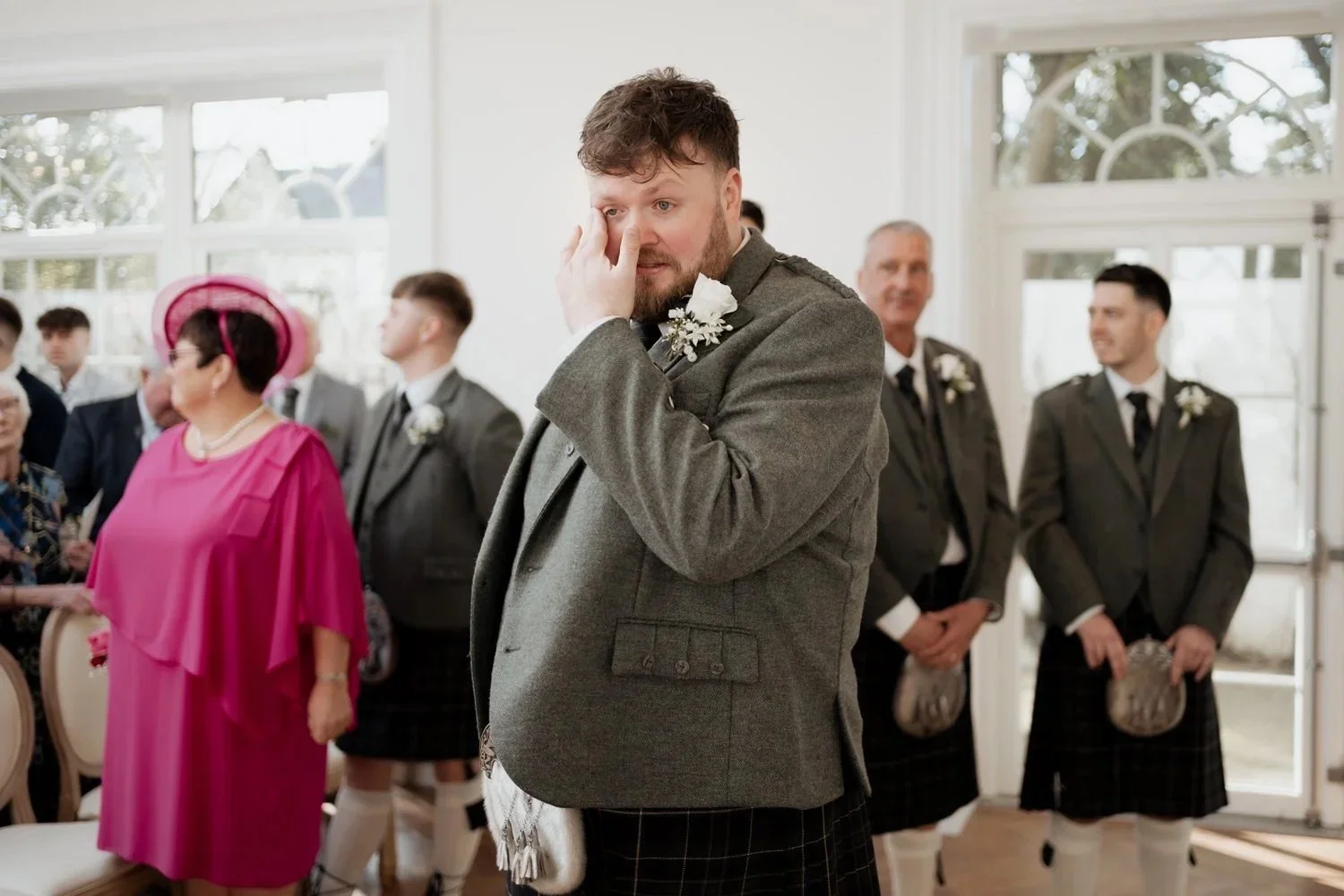 Groom visibly emotional during the ceremony, tears streaming down his face, surrounded by family witnessing a genuine moment of love