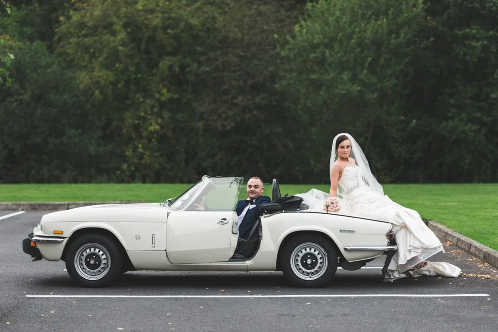 Bride and groom with a vintage white convertible car at the Dunsilly Hotel near Antrim
