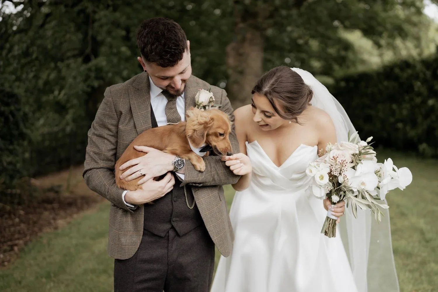Bride and groom sharing a joyful moment with their beloved dog on their wedding day, celebrating what matters to them