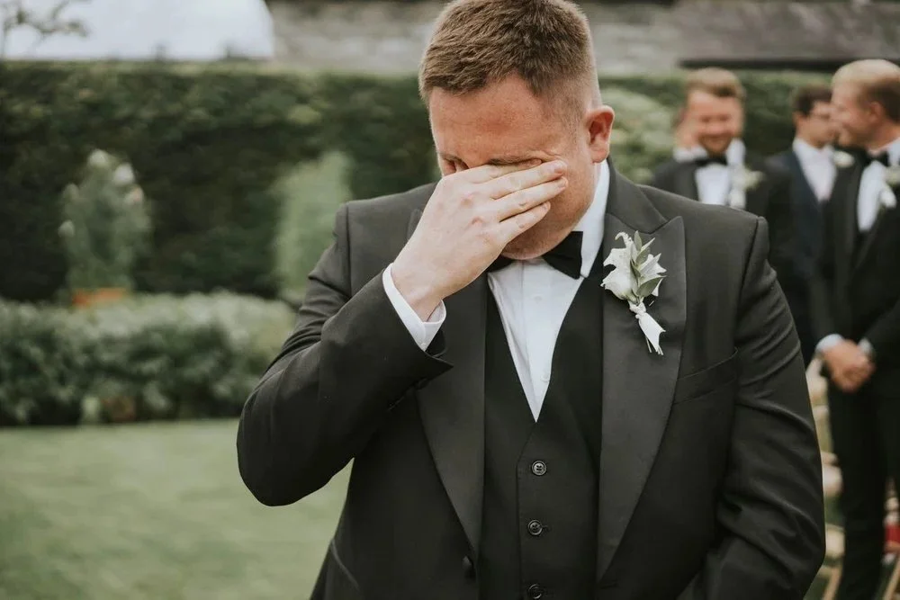 Groom wiping away happy tears during his wedding ceremony in Northern Ireland, with groomsmen smiling in the background, photographed by Pure Photo N.I.