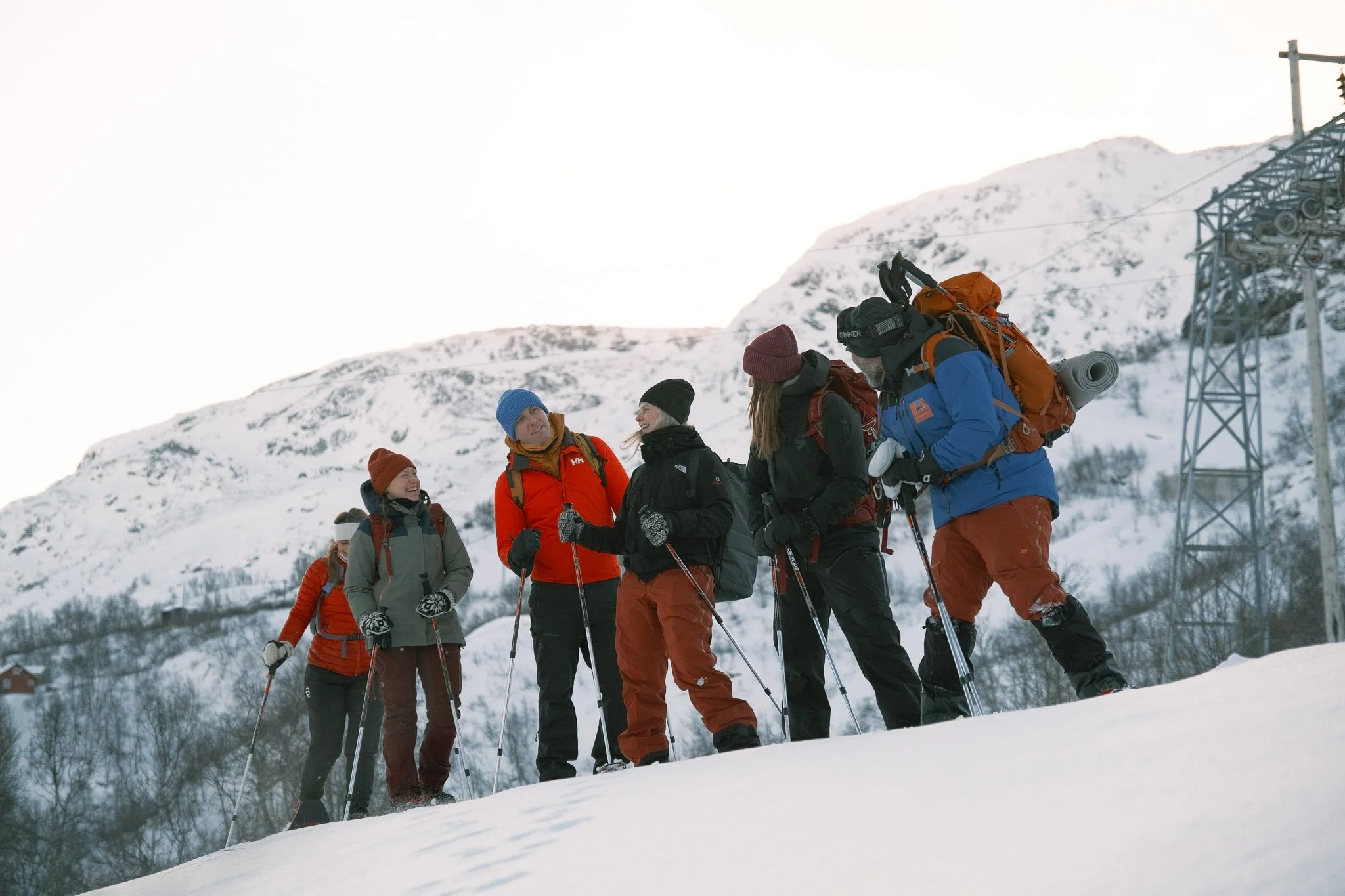 En gruppe mennesker i de snødekte fjellene som vandrer med truger og ler