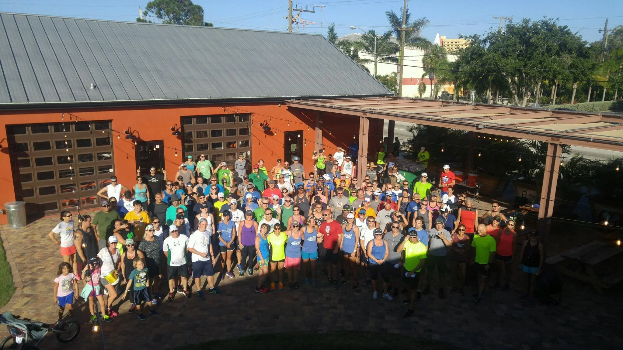 Large group of people gathered outside a building, dressed in athletic clothing, preparing for a run or walk event.