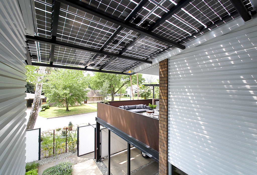 Thin-film photovoltaic solar panels create a generous entry porch roof cover with beautiful dappled light while generating electricity.