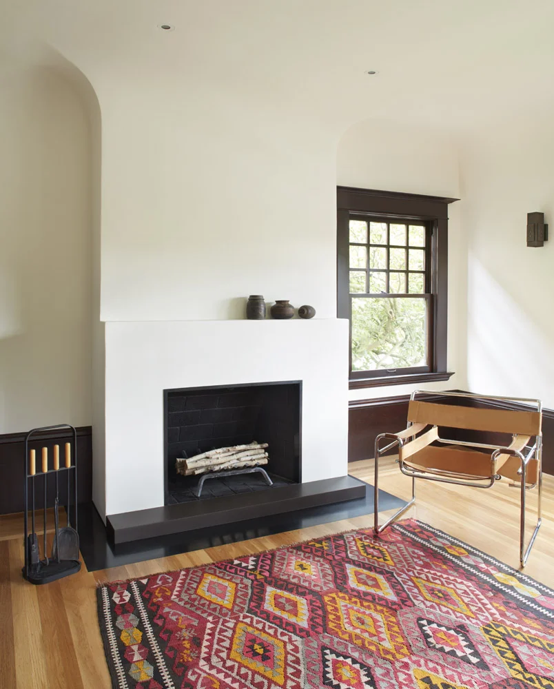 rebuilt fireplace, hot rolled steel hearth and concrete step. Traditional fireplace redesigned into a modern feature. Marcel Breuer Wassily chair and antique killim rug. 