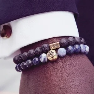 Photo of a black man’s wrist with two beaded bracelets.