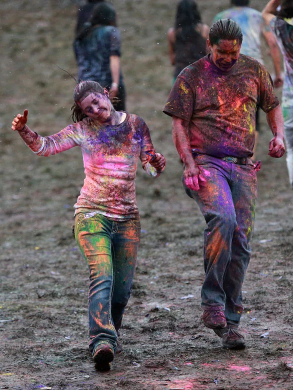 Festival goers skip down a muddy hill during a rain storm at the Holi Festival of Colors at the Sri Sri Radha Krishna Temple in Spanish Fork on Sunday, March 30, 2014.