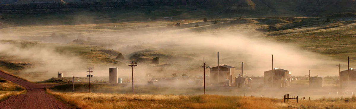  Stirred up dust from a passing coalbed methane truck floats over a cluster of compressor stations, after the truck has disappeared down SA Road, towards Tooter Rogers' ranch. This county road serviced only a handful of vehicles prior to the onset of