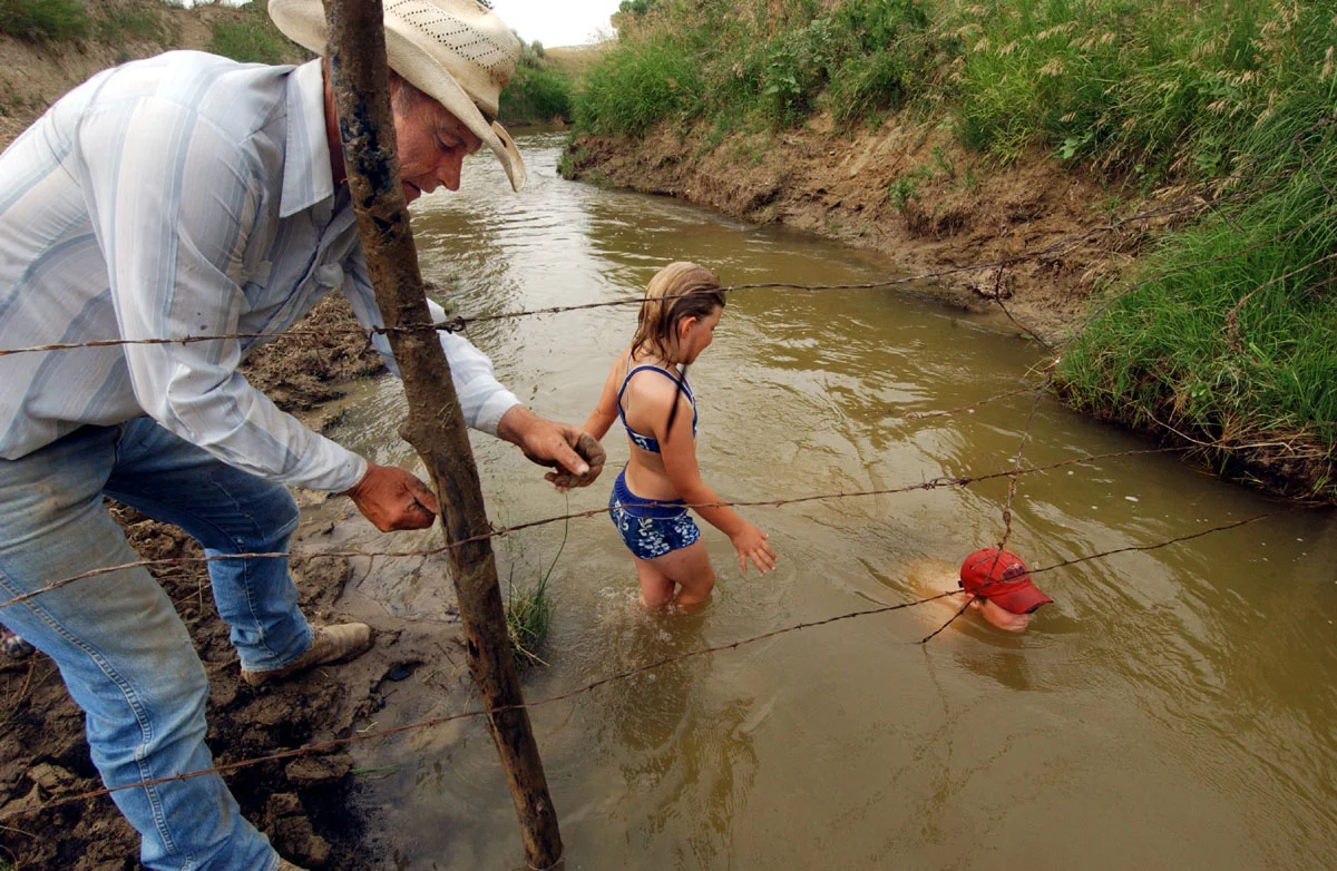  Gary Packard fixes fencing while his grandchildren, Hannah Rockafellow, 8, and Mason Rockafellow, 11, play in Crazy Woman Creek on the Packard's Arvada ranch. Black Diamond, who holds the lease to mineral rights under neighboring land, is trying to 