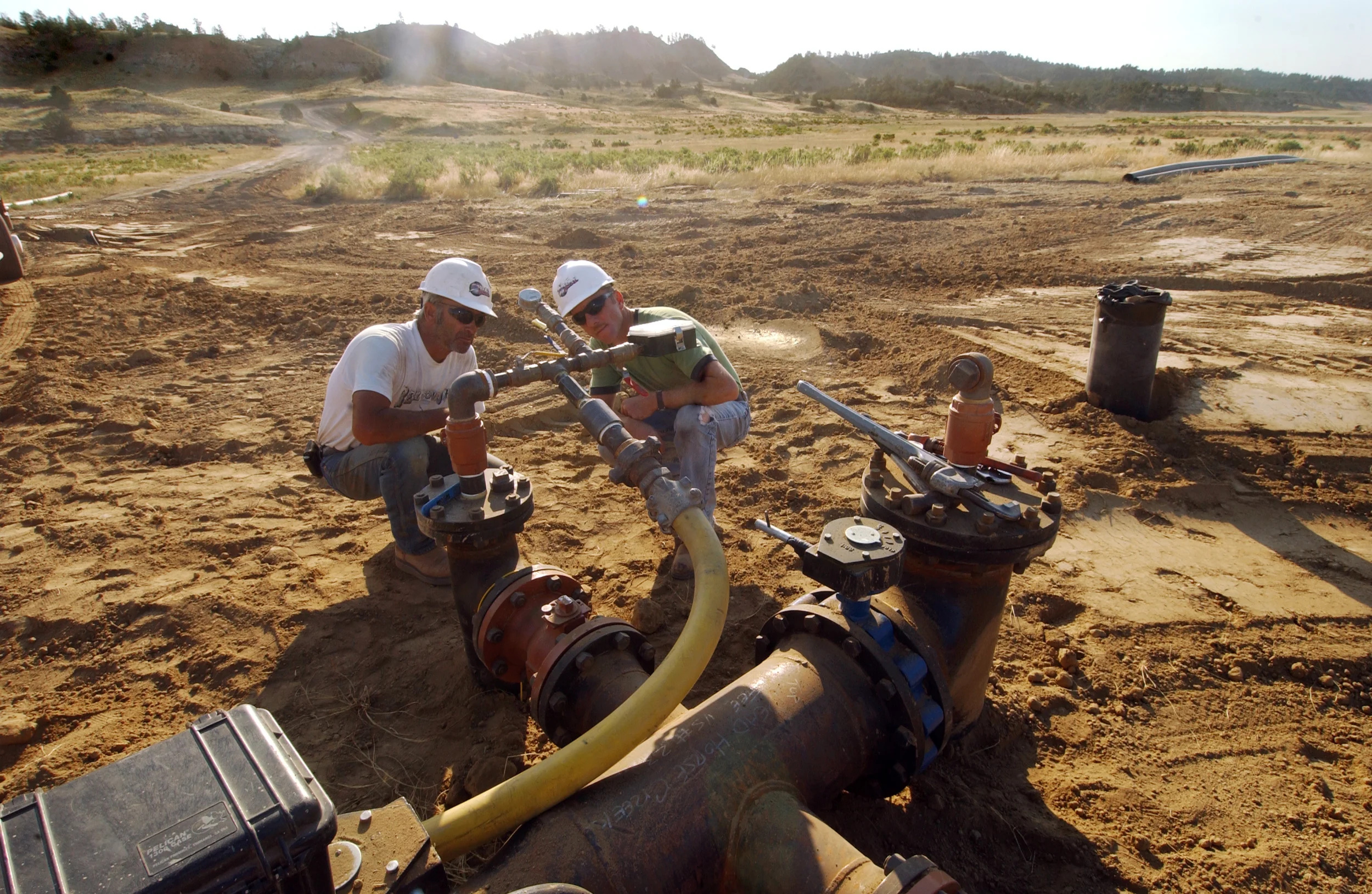 Jerry Collins and Delbert Kamdamas charge up an air compressor to check for leaks in pipeline they are installing throughout Tooter Rogers' ranch. While the Rogers own the surface land, J.M. Huber owns the lease to subsurface mineral rights. Through