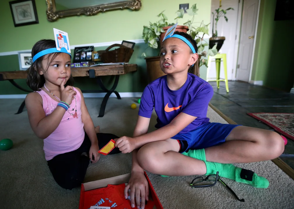  Tifa Ward and Lota Ward play the game Hedbanz after school at home in Layton on Wednesday, May 4, 2016.  