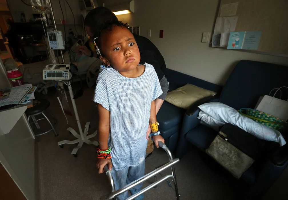  Lota Ward uses a walker to stand and look out the window of his hospital room while recovering from his fourth brain surgery for a teratoma tumor at Primary Children's Hospital in Salt Lake City on Tuesday, April 7, 2015. For a while after the surge