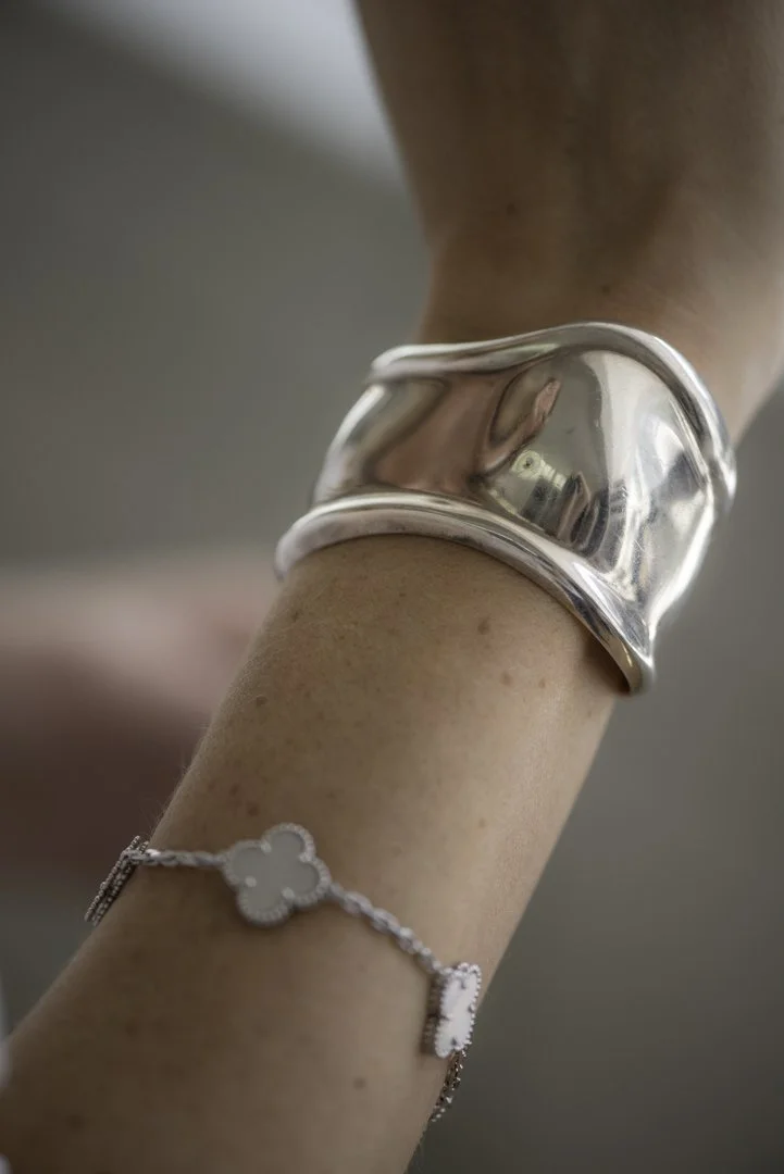 product photography close up of a woman's arm wearing chunky silver bracelet and a dainty silver bracelet together