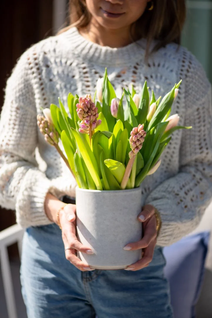 product photography of a woman holding flowers in a modern concrete vase