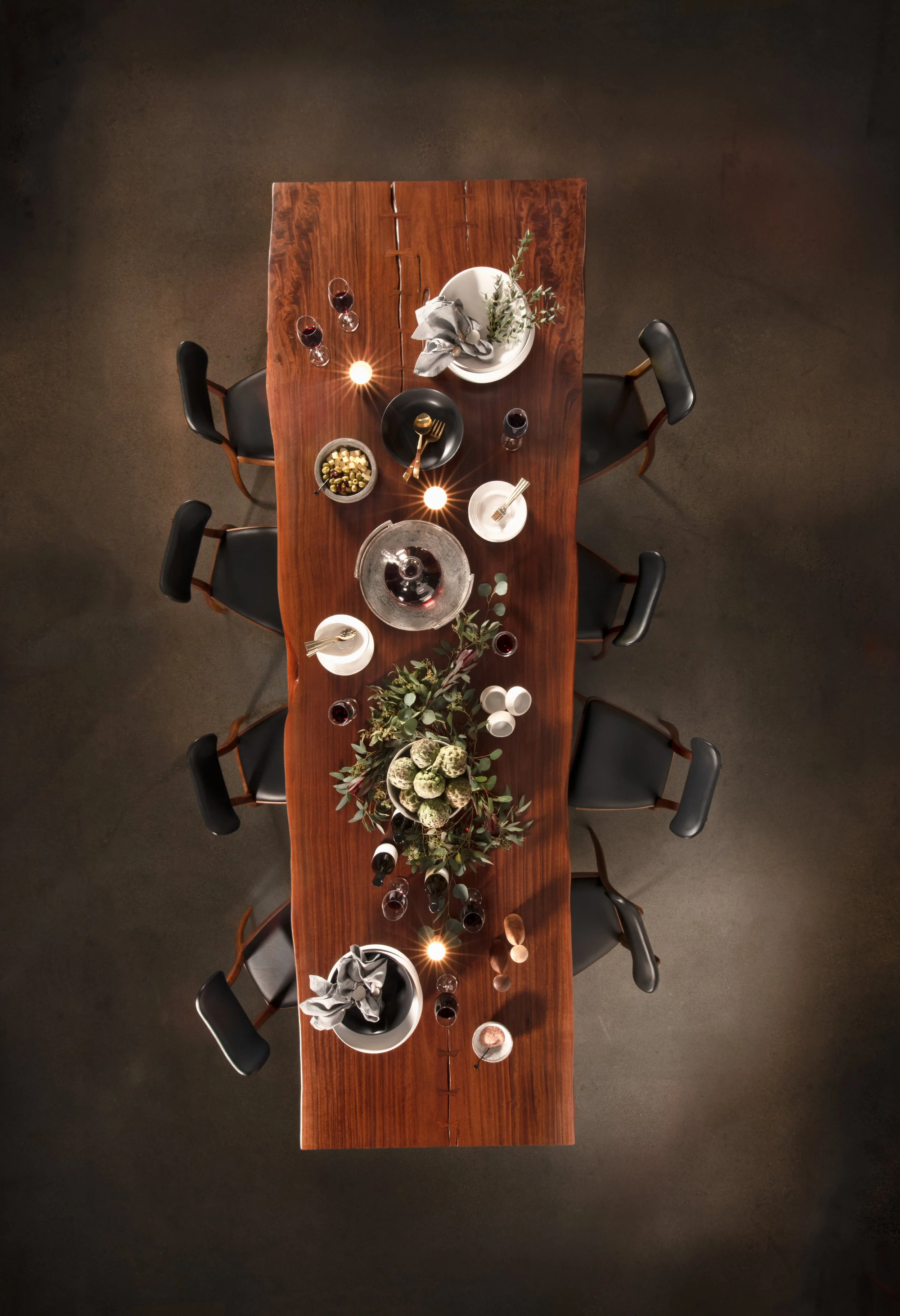 product photography of a styled luxury wooden dining table Birds Eye view. the table is set and there are chairs set up around it. shot for Reduxwood West