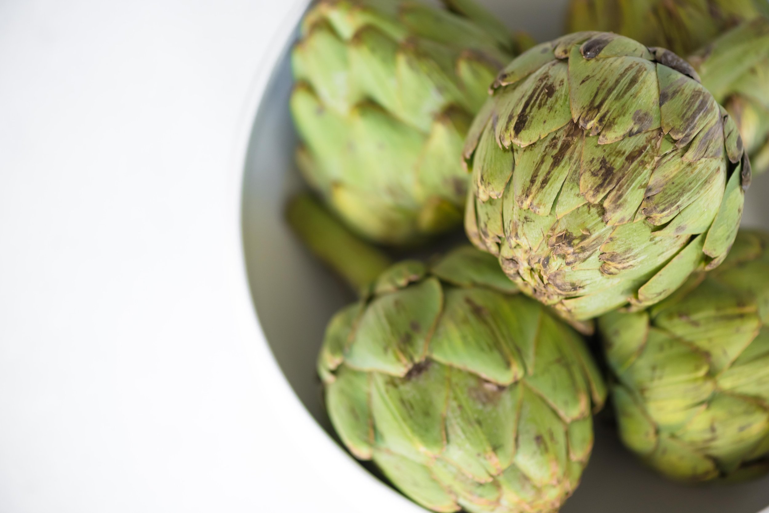 product photography and food photography of fresh bright green artichokes in a bowl