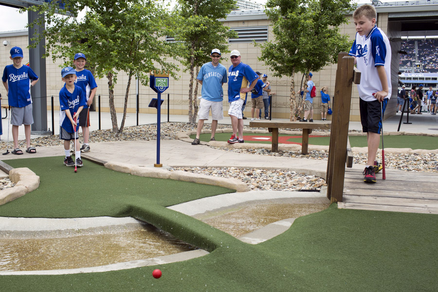 Brenden, second to right, hits a golf ball in a mini-golf game as Teegan, Caden, Mark, Daryl and Dustin look on.