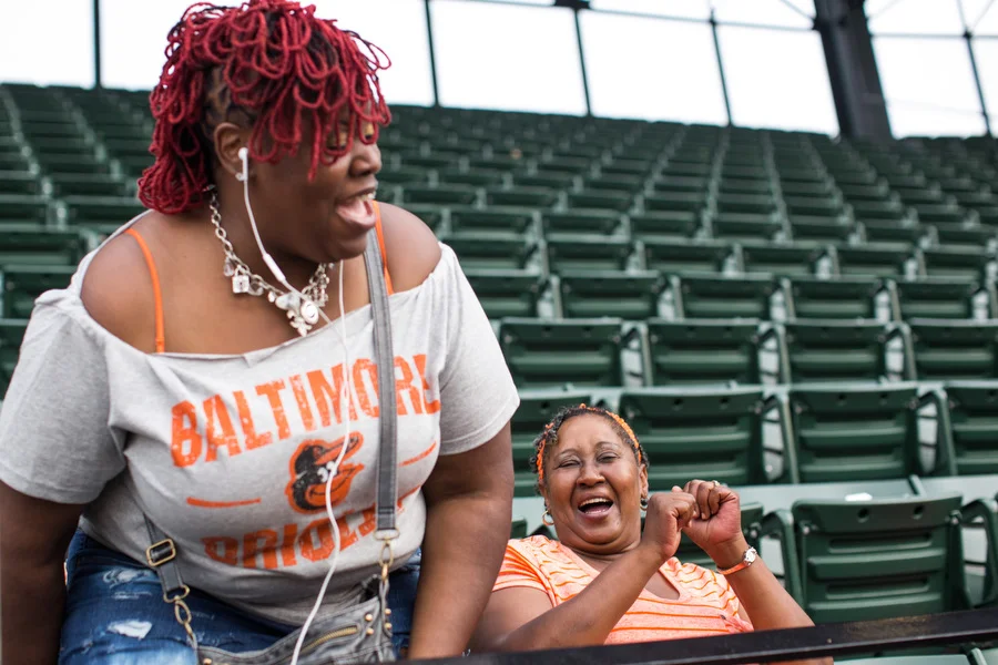 Social worker Joy Aisha Bell laughs with Joann Wilson, who was attending her first baseball game ever. 