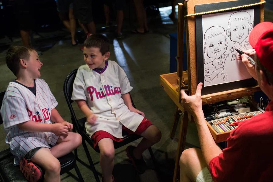 Cash, left, and Jaden get a caricature drawing at the game. 