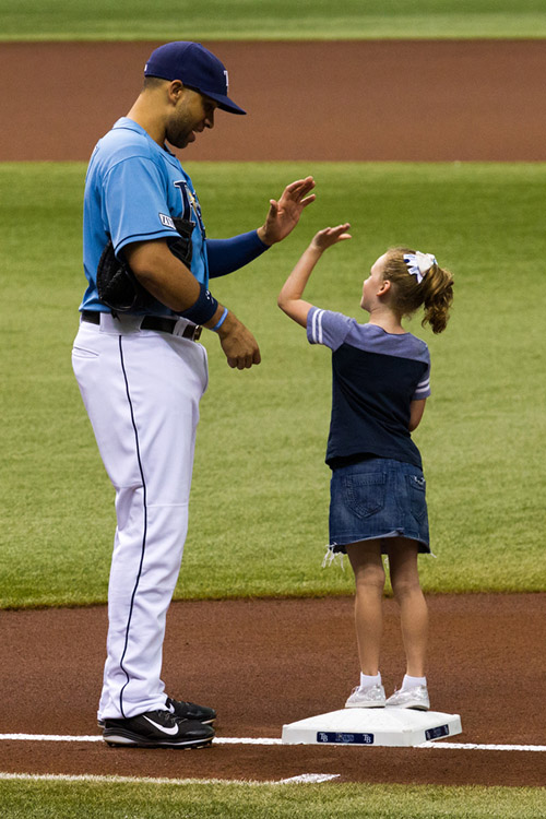 First baseman James Loney high fives a fan before the start of the game. 