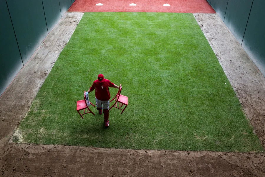 A Phillies bullpen catcher moves chairs out of the rain. 