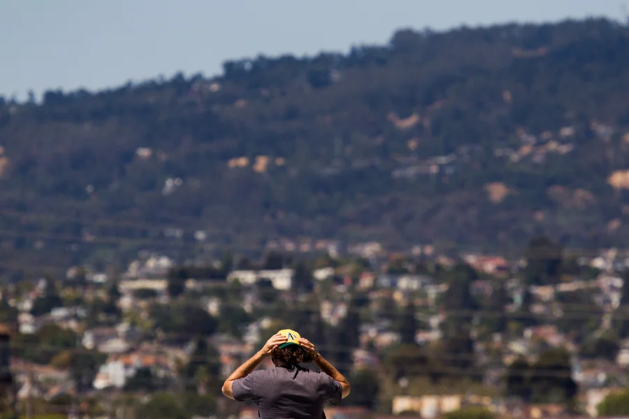 With the hills that lead to Redwood Regional Park in the background, a fan adjusts his cap.