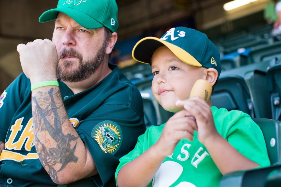 Lance Malone and his 7-year-old son Patrick, a catcher in little league, watch the game.