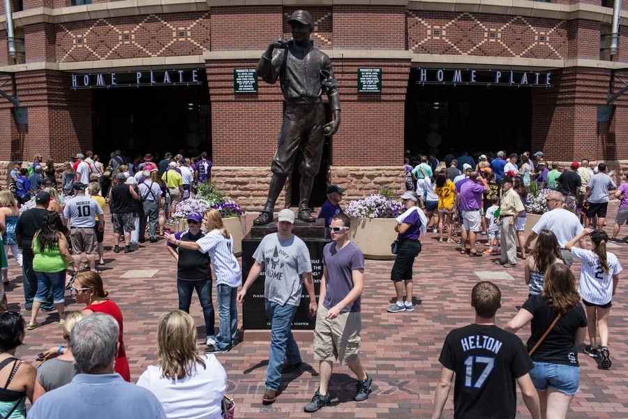 A statue of Branch Rickey stands in front of the Coors Field home plate entrance. A quote inscribed on the statue reads, "It is not honor that you take with you but the heritage you leave behind."