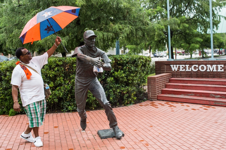 Robert Brandon shields a statue of former Astros second baseman Craig Biggio from the rain with his umbrella.