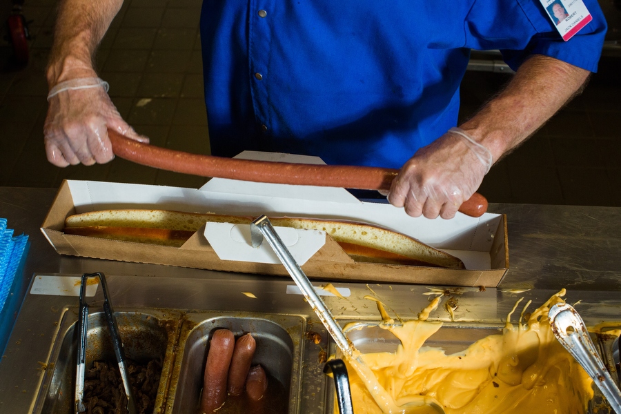 A food service employee prepares a "Boomstick," a 2-foot-long, one-pound hot dog topped with nacho cheese, jalapeños, chili and onions. The hot dog gets its name from the nickname Nelson Cruz gave to his bat. 