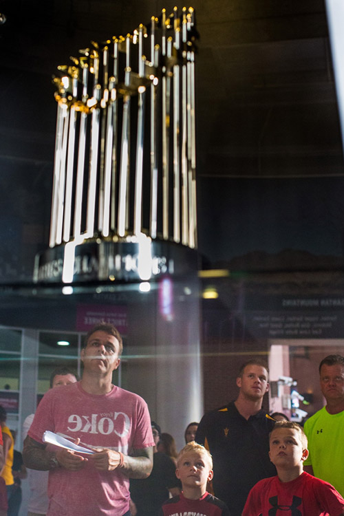 Fans watch highlights from the final game of the 2001 World Series in which the Diamondbacks clinched the World Series on a tv just above the World Series trophy. 