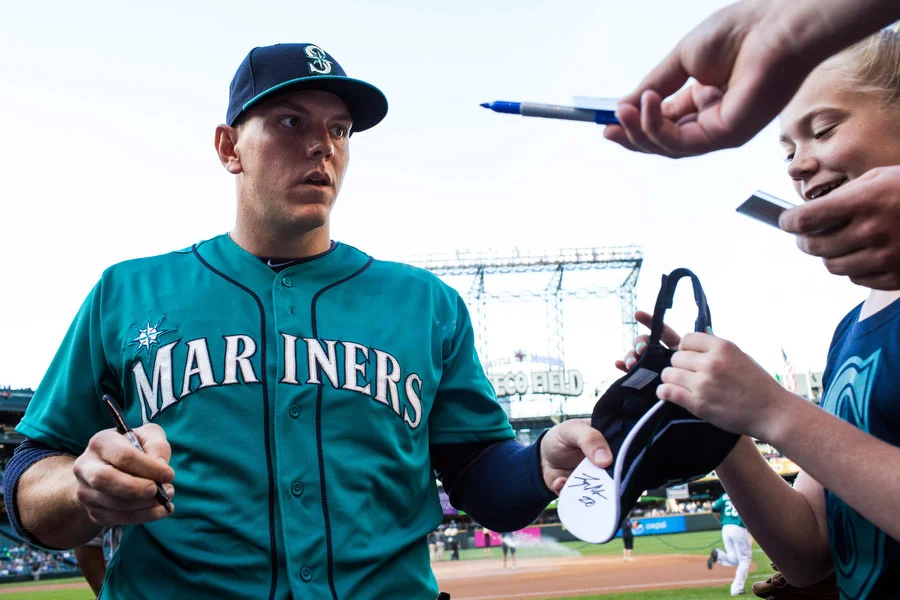 Mariners first baseman Logan Morrison signs autographs before the game. 