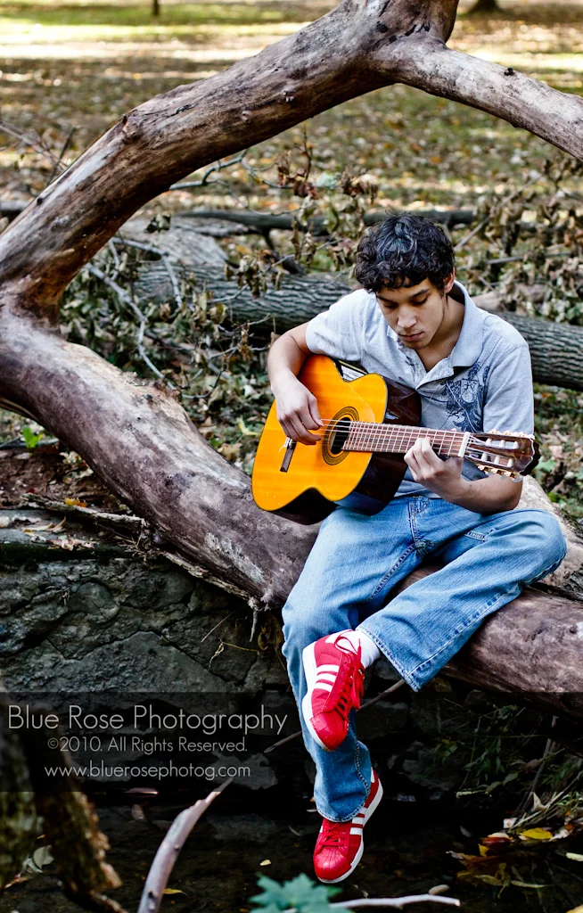 Daniel sitting on a dead tree. In front of dead trees. ...Playing an instrument made from dead trees...