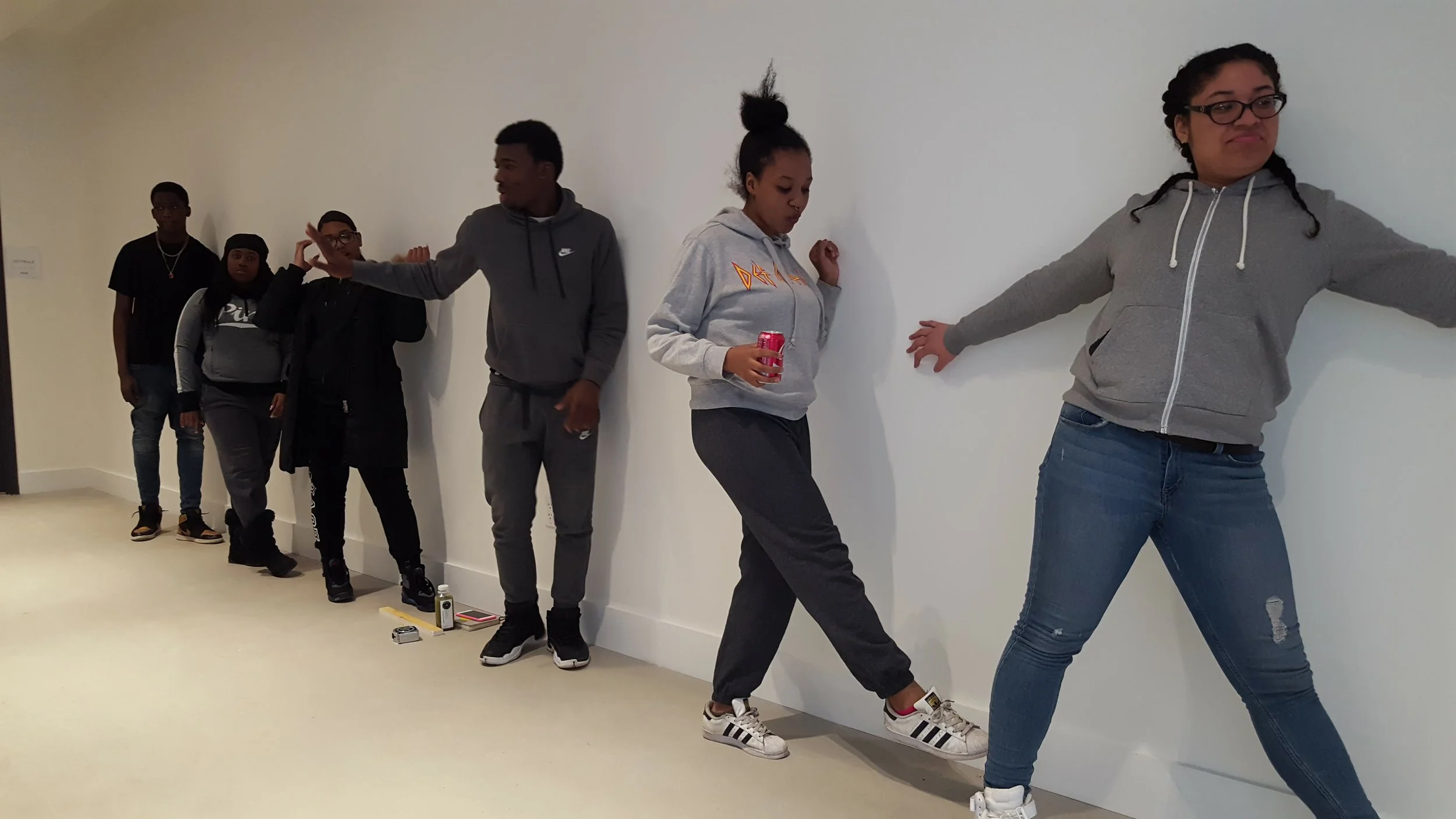 CAW Youth Apprentices block out their poses on the blank wall. 