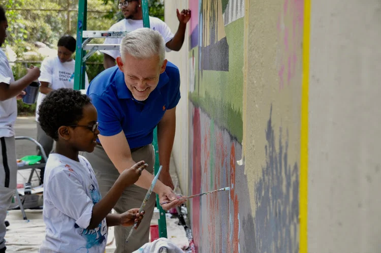 NYC Council Member Jimmy Van Bramer paints with a Queensbridge resident. Younger children were invited to make temporary art on the lower portion of the wall throughout the day. Photo courtesy LIC Partnership. Used by permission.