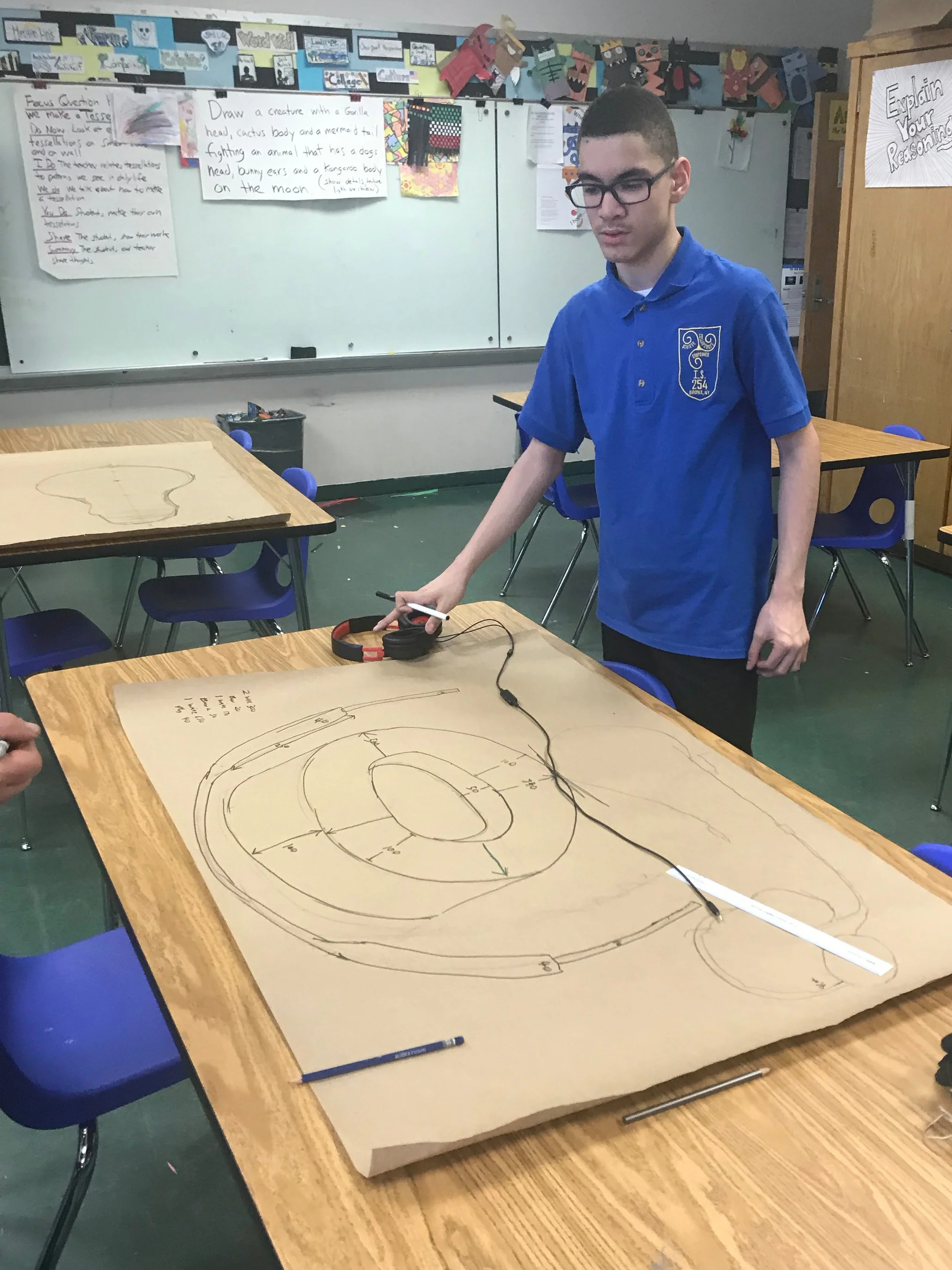 An MS 254 student with a scale drawing of his headphone many times larger than life.