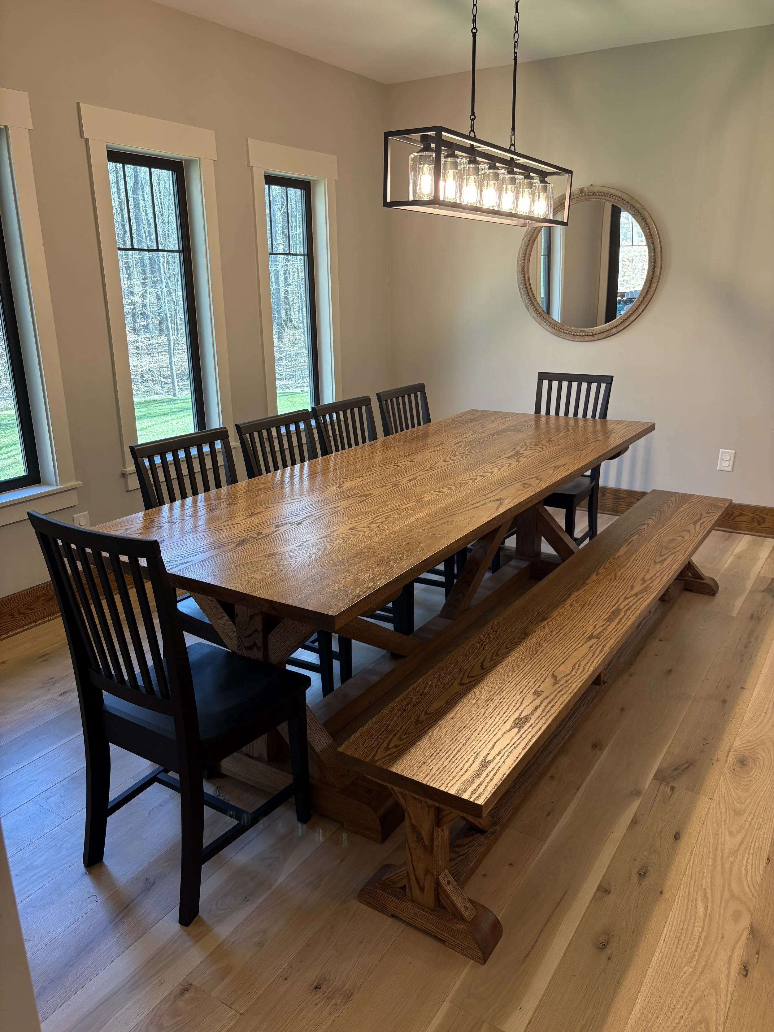 Large solid wood trestle dining table with matching bench and seating for a gathering