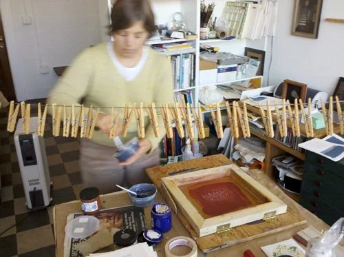  Alison mixing silkscreen inks in her studio. &nbsp;The silkscreen is the hinged square frame laying on the table to her right. 
