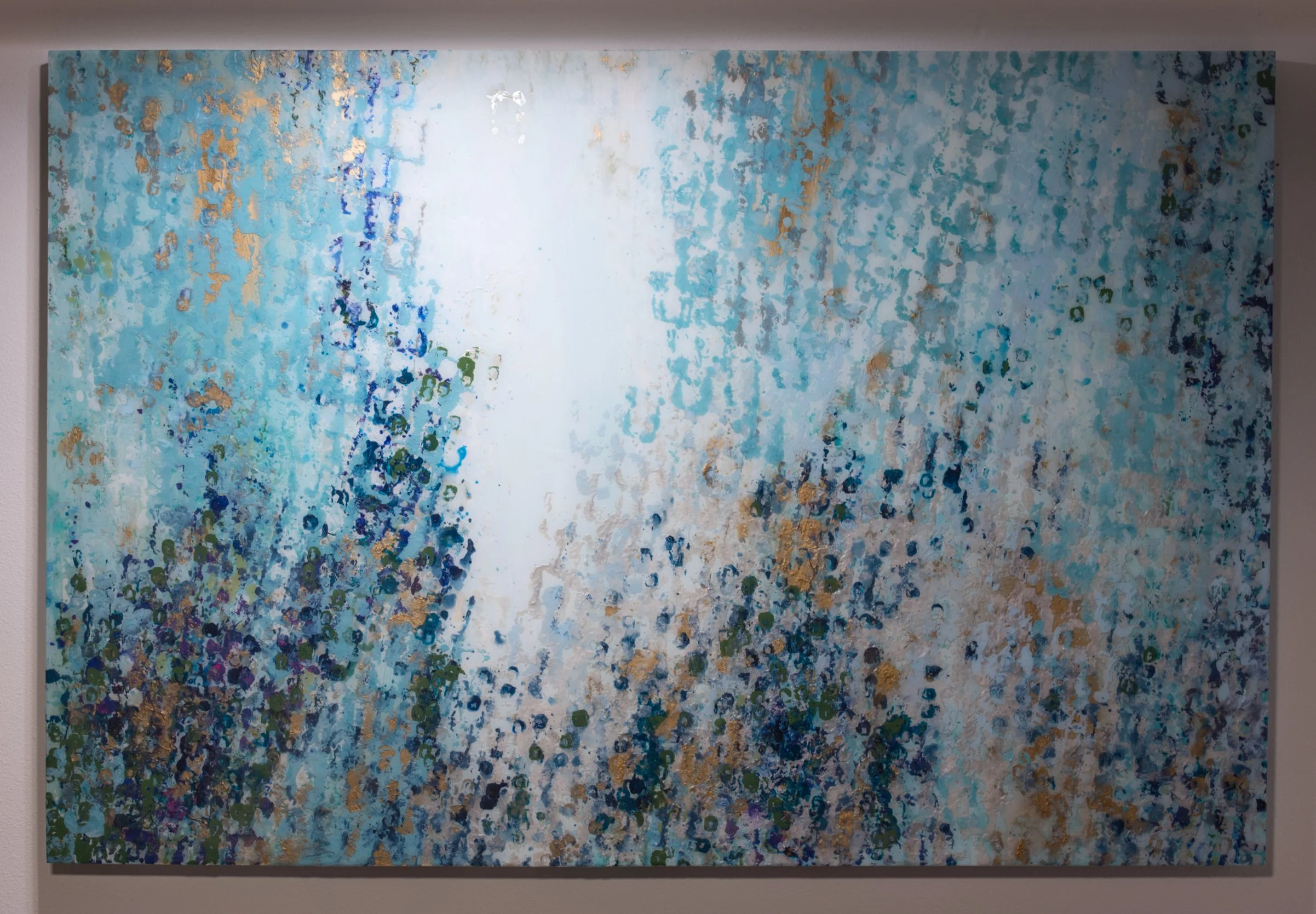 Abstract painting with blue, green, white, and gold dots on a canvas