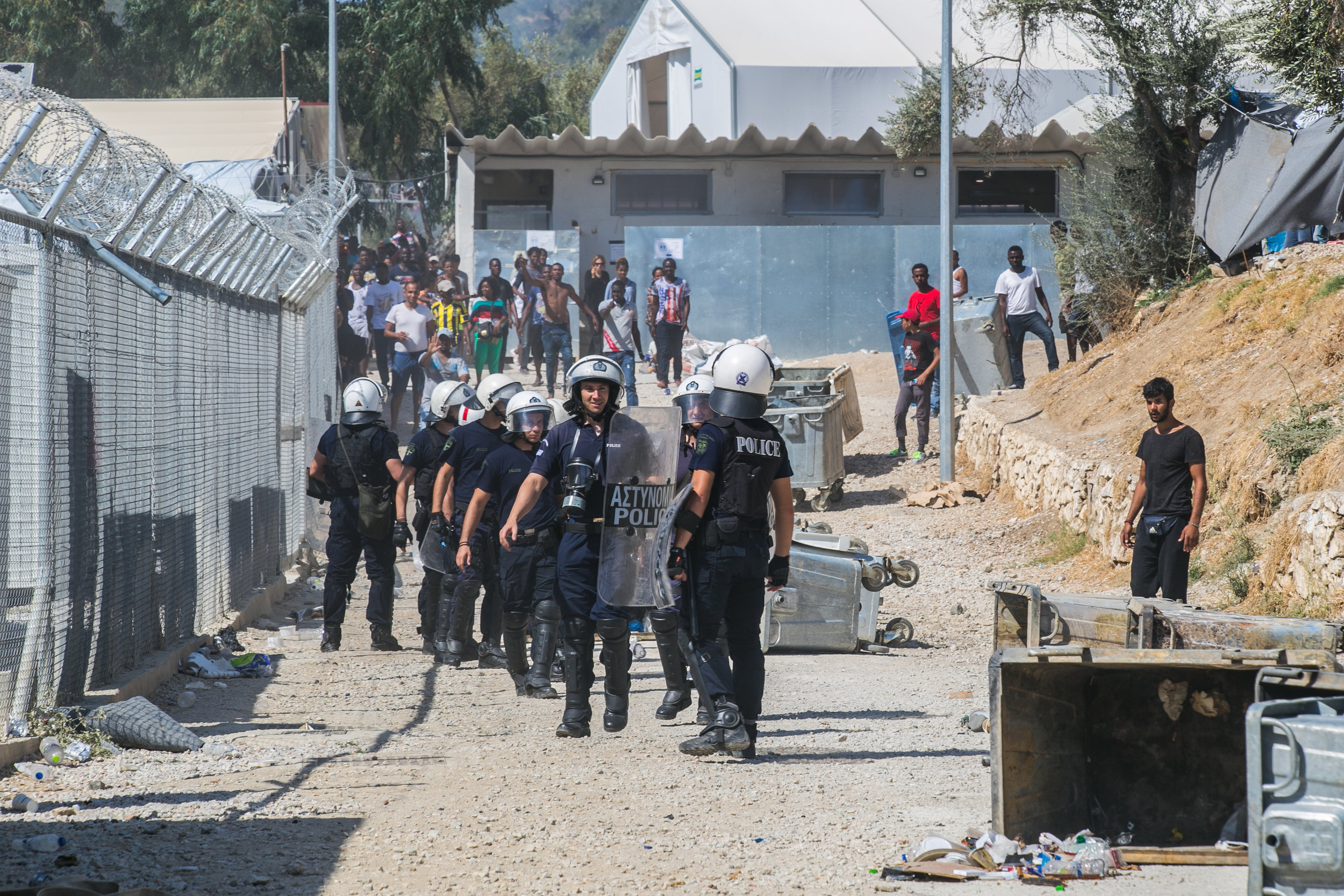  Riot police react as a crowd of Turkish and Syrian refugees begin to throw rocks outside the entrance to a camp in Moria, Lesvos. The riot began earlier this morning with refugees flipping dumpsters, lighting trash on fire, and taunting police. Afte