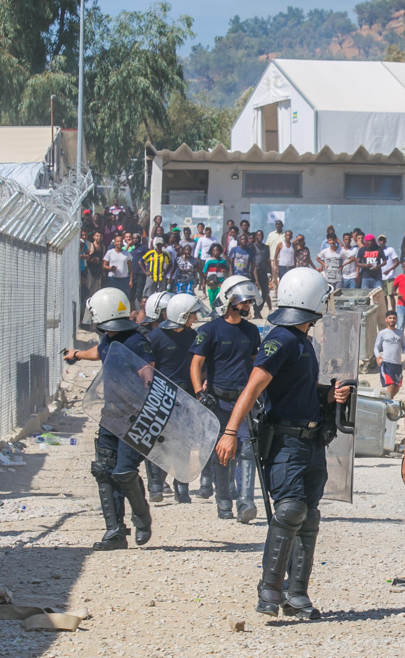   mikeschwarzthekid Riot police react as a crowd of Turkish and Syrian refugees begin to throw rocks outside the entrance to a camp in Moria, Lesvos. The riot began earlier this morning with refugees flipping dumpsters, lighting trash on fire, and ta