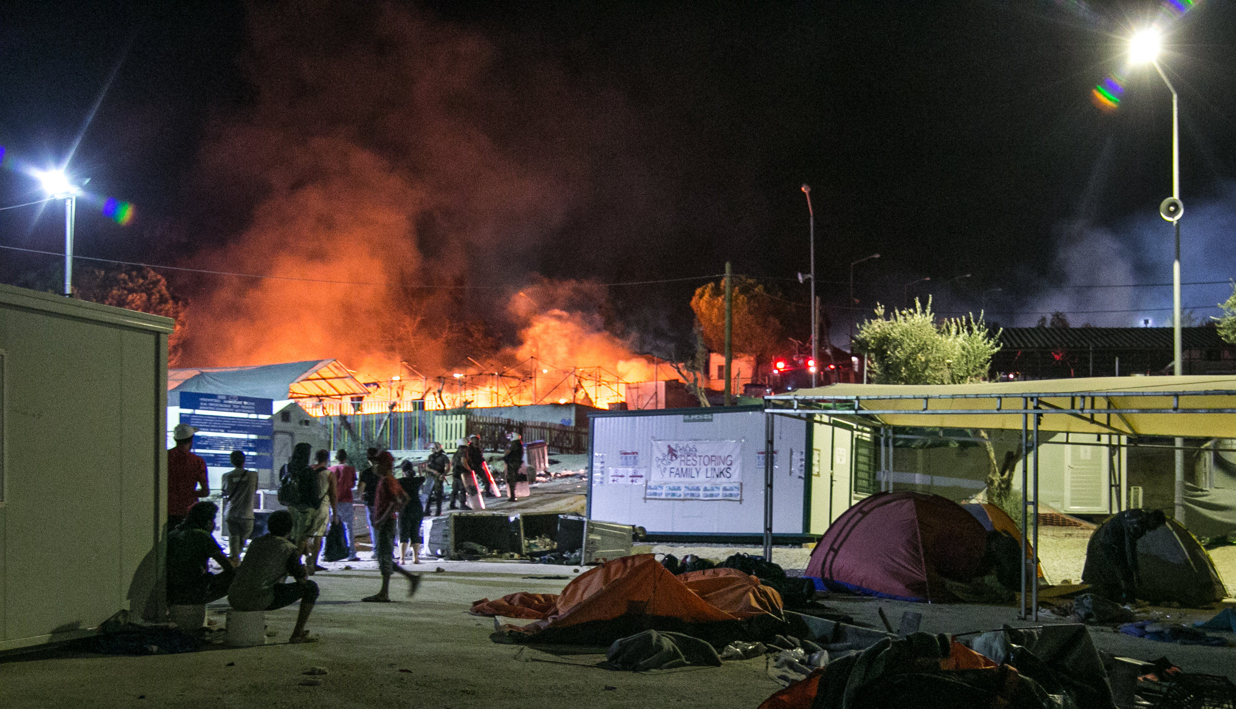  Migrants and police look on as one of the largest camps in Lesvos burns to the ground. The violence began early this morning with small incidents of rock throwing and trash burning, but quickly worsened as the day went on. According to several South