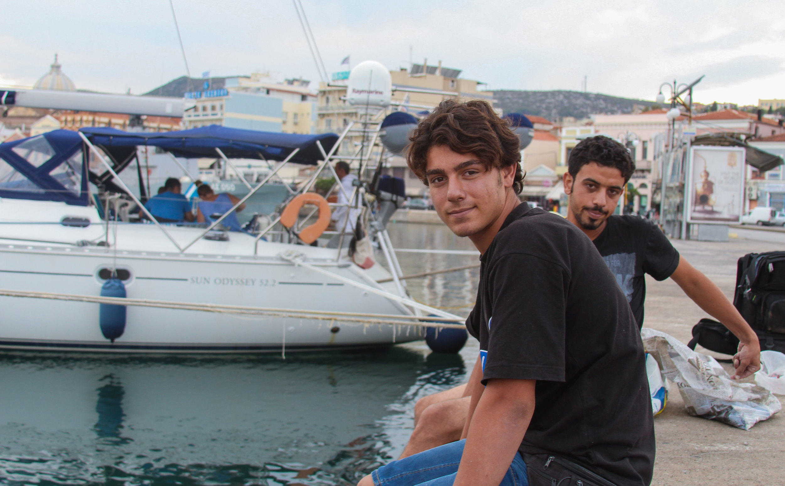  Two Syrian migrants fish off the dock in the port of Mytiline 